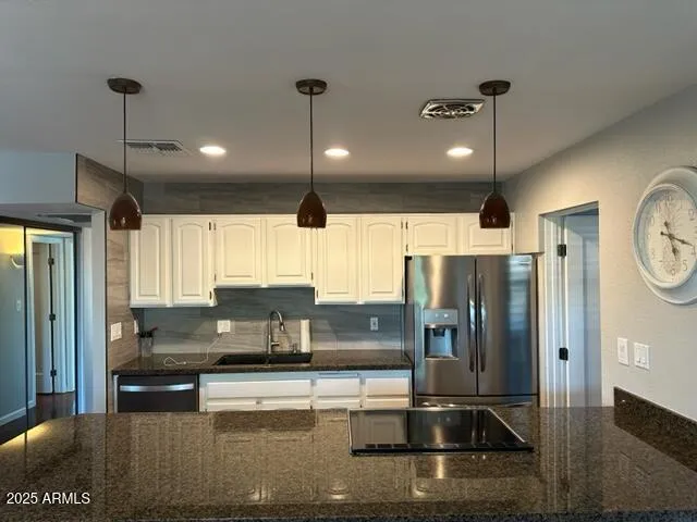 a kitchen with stainless steel appliances granite countertop a refrigerator a sink and a stove
