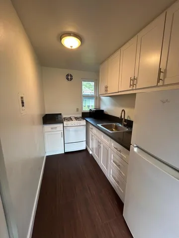a kitchen with granite countertop a sink a stove and cabinets