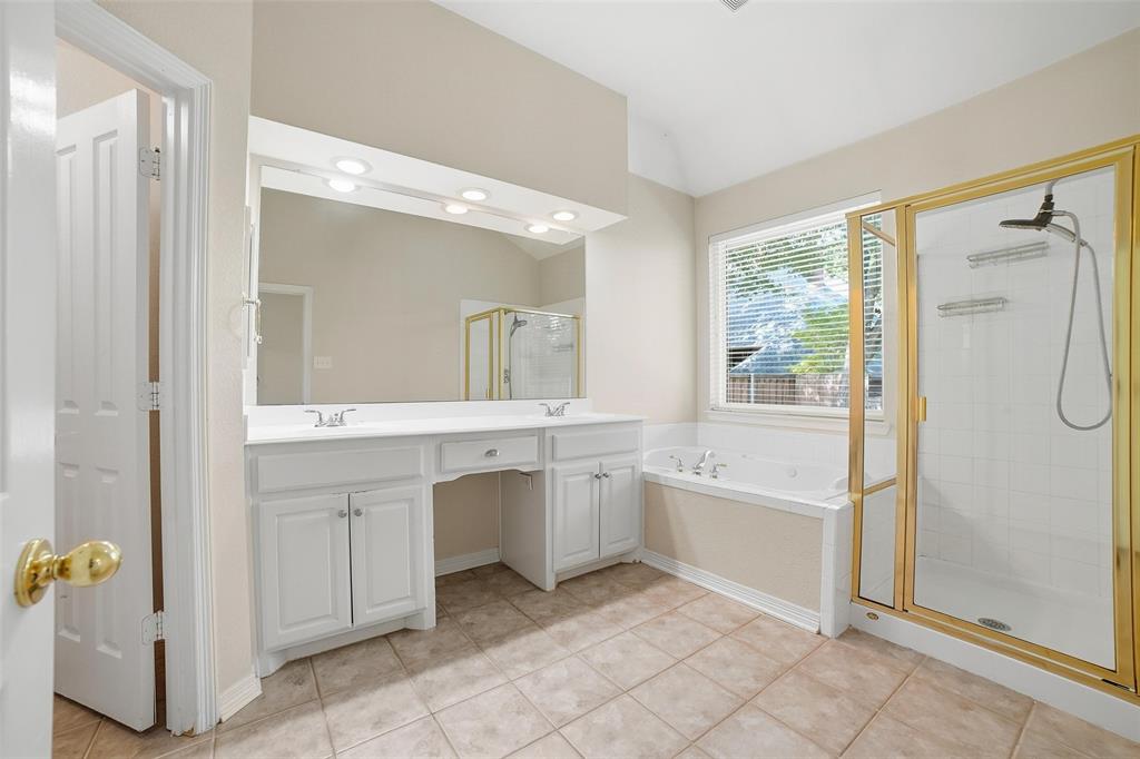 7909 Enclave Way Dallas, TX 75218 - Photo 13 of 21 Full bathroom featuring double vanity, light tile patterned floors, a bath, a stall shower, and lofted ceiling