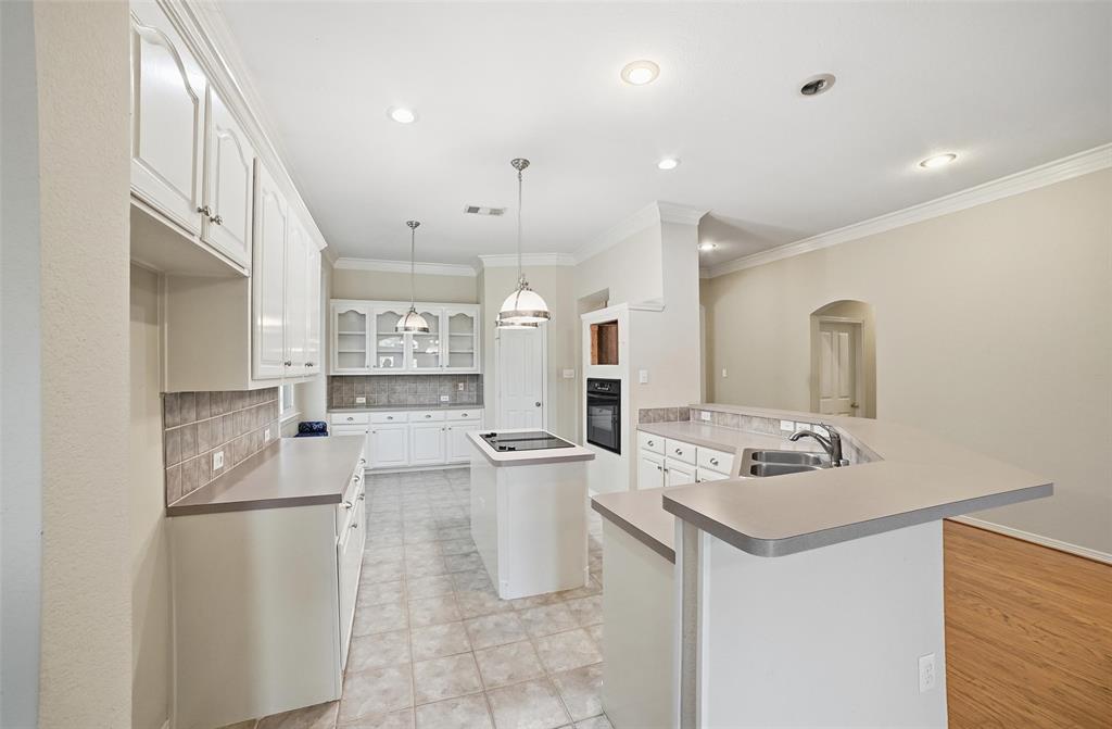 7909 Enclave Way Dallas, TX 75218 - Photo 6 of 21 Kitchen featuring tasteful backsplash, a kitchen island, arched walkways, crown molding, and white cabinets