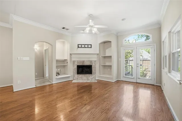 an empty room with windows fireplace and a kitchen view