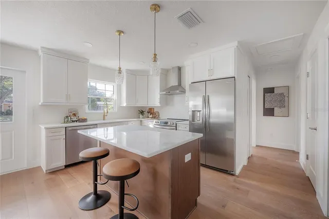 a kitchen with stainless steel appliances granite countertop a sink a refrigerator and a refrigerator