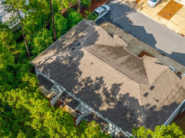 an aerial view of a house with outdoor space and trees all around