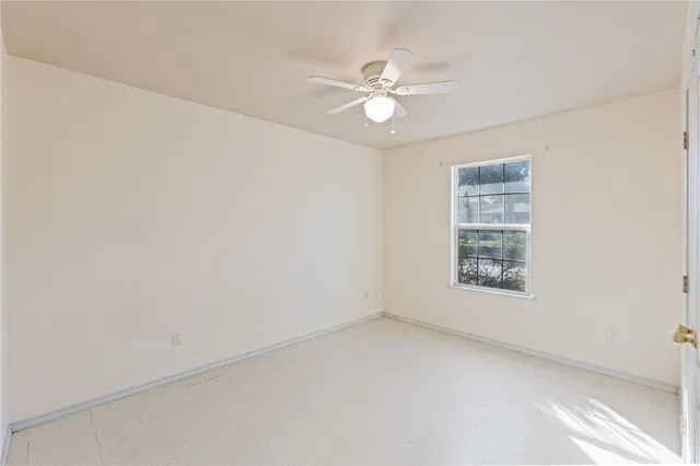 an empty room with windows and fan