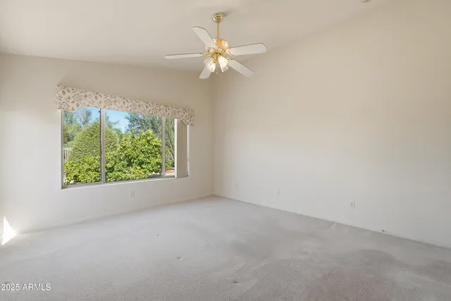 an empty room with chandelier fan and windows