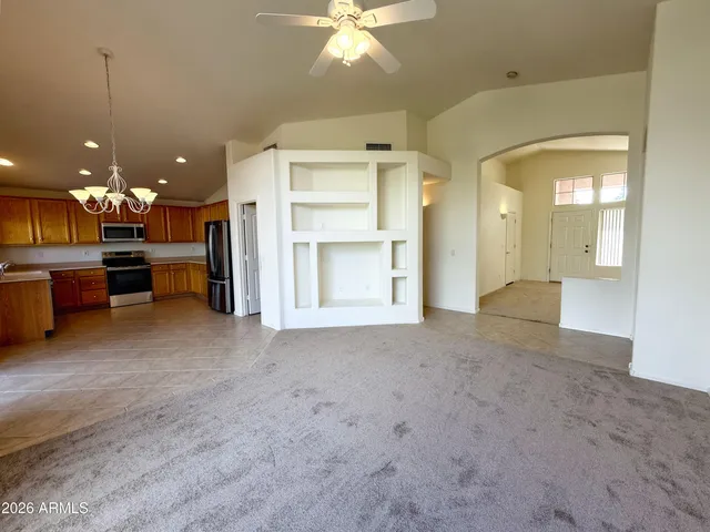 a view of an empty room with a window and kitchen view