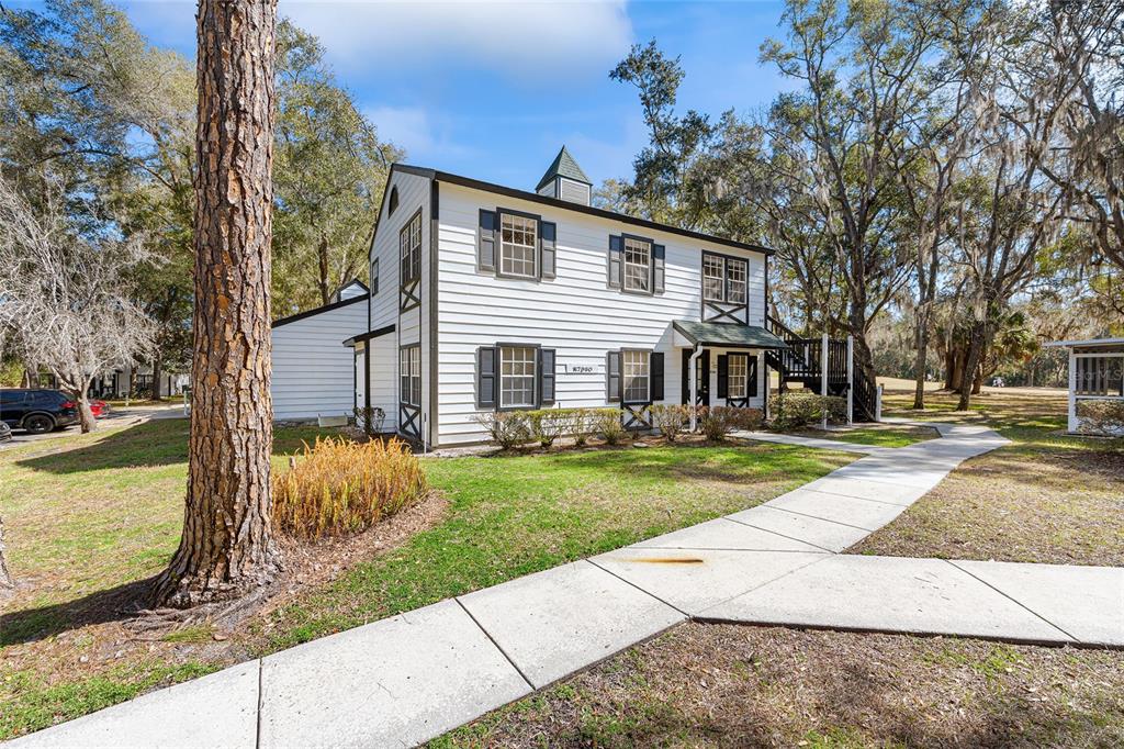 7930 Midway Dr Terrace, Unit R201 Ocala, FL 34472 - Photo 2 of 29 a view of a white house next to a yard with big trees