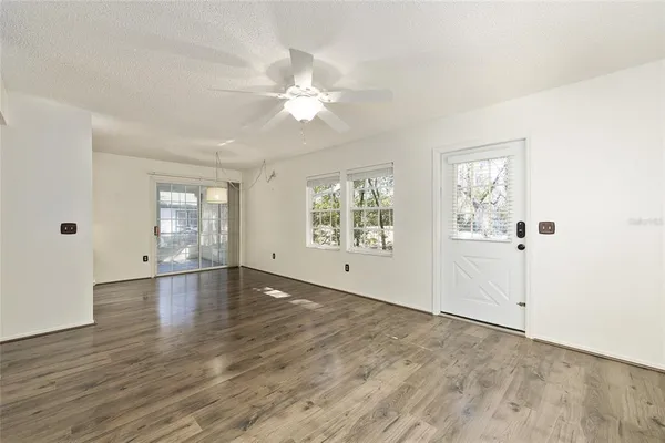 an empty room with wooden floor fan and windows