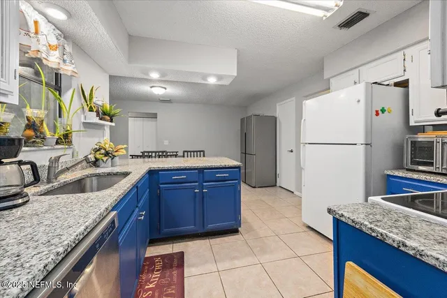 a kitchen with granite countertop a sink a counter space and stainless steel appliances