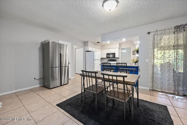 a kitchen with stainless steel appliances granite countertop a refrigerator a stove a dining table and chairs