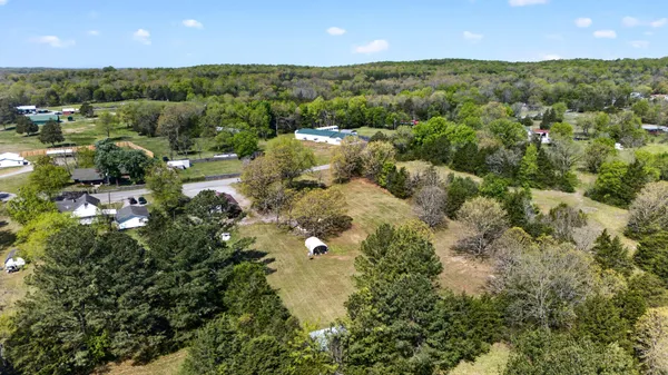 an aerial view of residential houses with outdoor space and trees