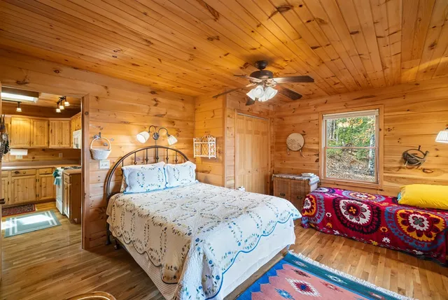 a bedroom with a bed a dresser and next to a window