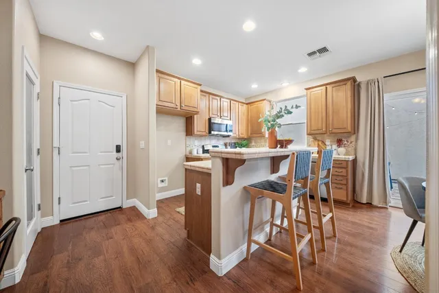 a kitchen with stainless steel appliances a refrigerator a stove a sink dishwasher and a dining table with wooden floor