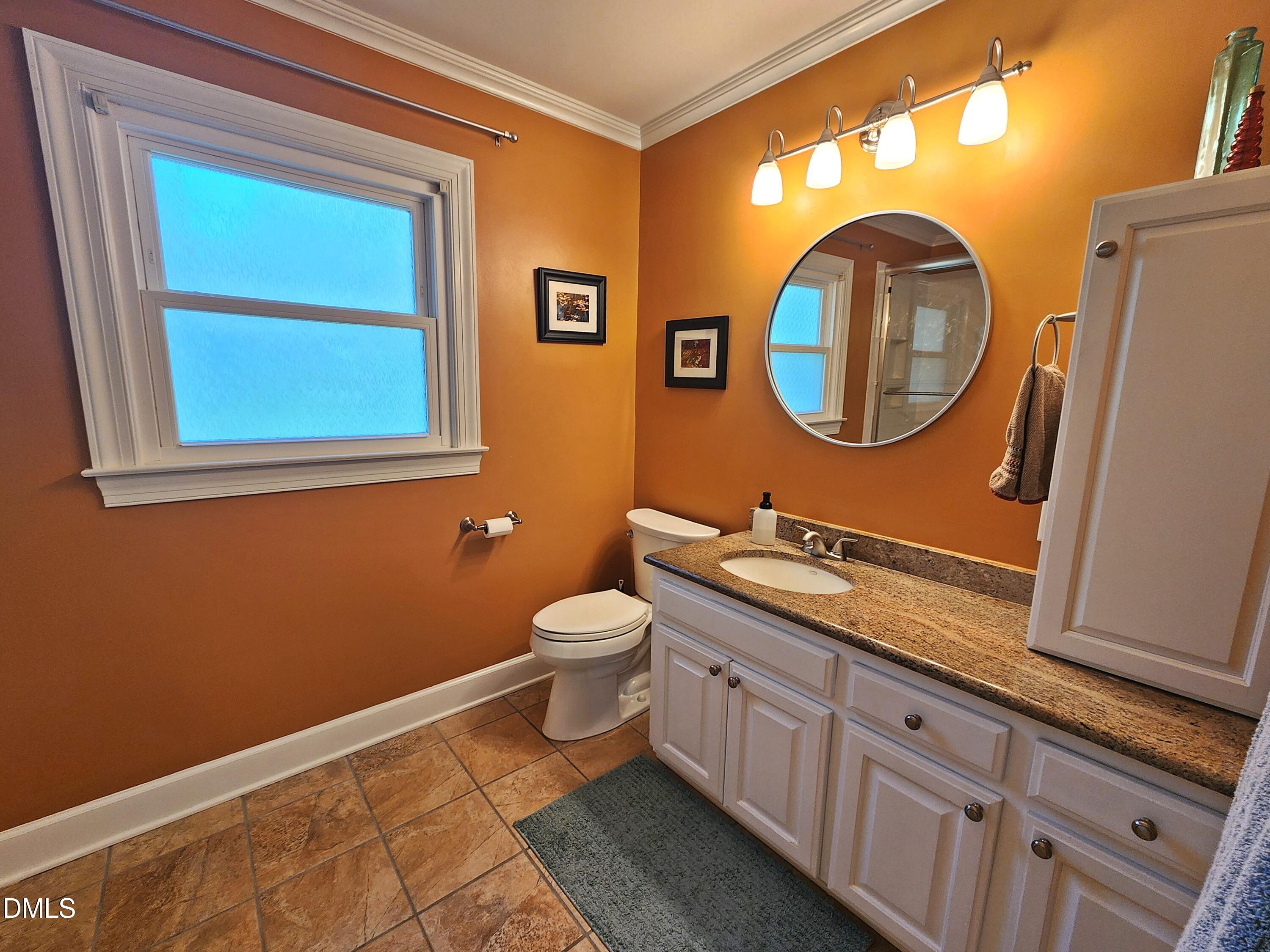 4704 Oak Park Road Raleigh, NC 27612 - Photo 42 of 62 a bathroom with a toilet a sink and a mirror