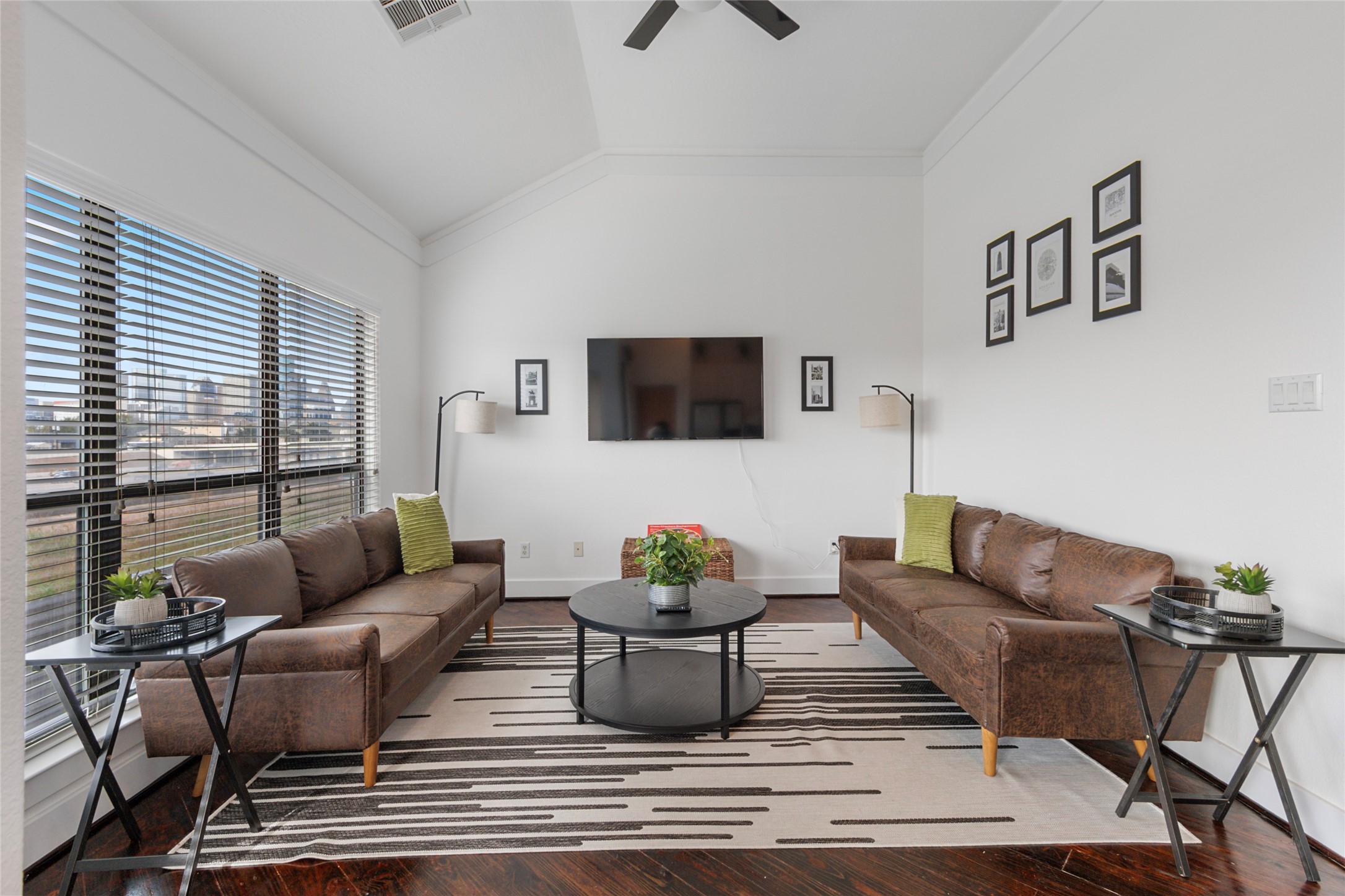 Bright open-concept living area with large windows, modern furnishings, and warm wood flooring, perfect for relaxing or entertaining.