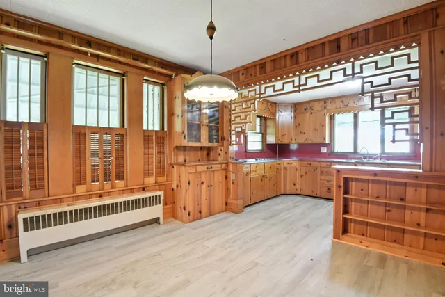 a view of a living room and kitchen with furniture an fan and wooden floor