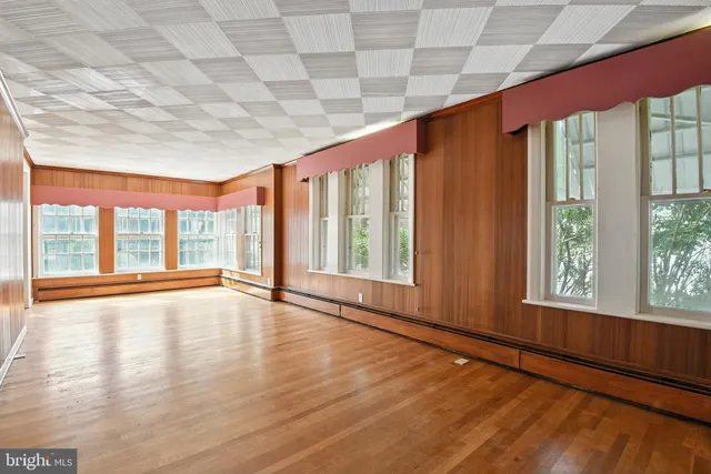 a view of an empty room with a window and wooden floor