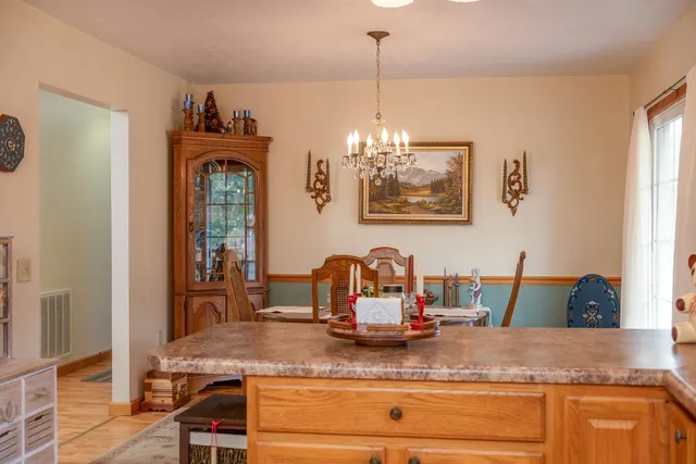 a kitchen with stainless steel appliances granite countertop a sink a stove and a dining table with wooden floor