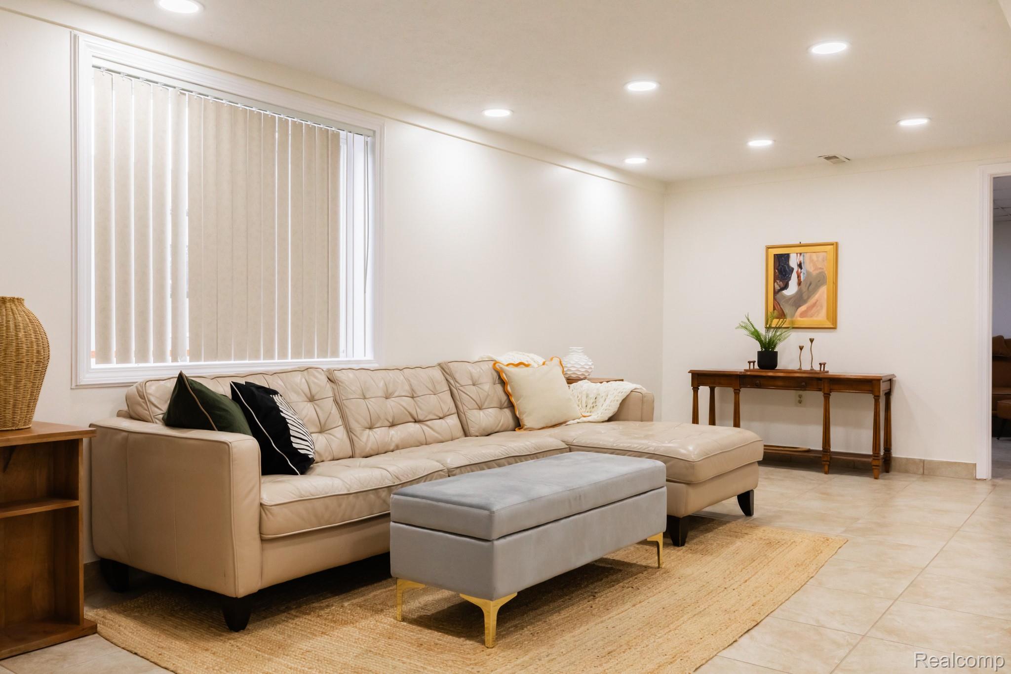 3882 Okemos Road Okemos, MI 48864 - Photo 30 of 50 Spacious living room with a sectional layout, neutral upholstered seating, tile flooring, recessed ceiling lighting, vertical blinds, and a console table with decorative accessories