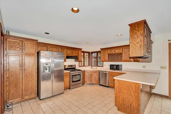 a kitchen with stainless steel appliances granite countertop a refrigerator oven a sink dishwasher and white cabinets with wooden floor