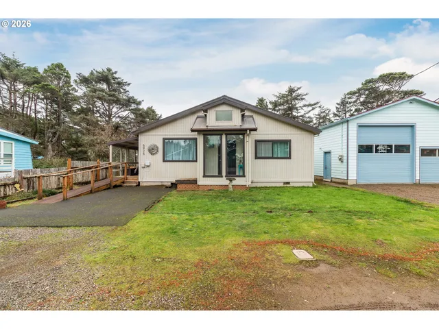 a view of a white house next to a yard with big trees