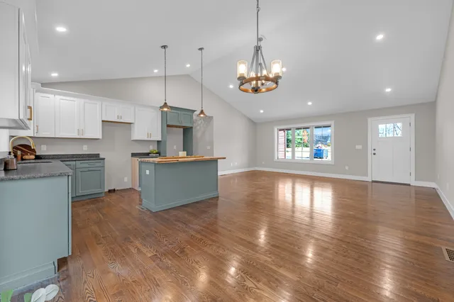 a view of an empty room with wooden floor and a ceiling fan