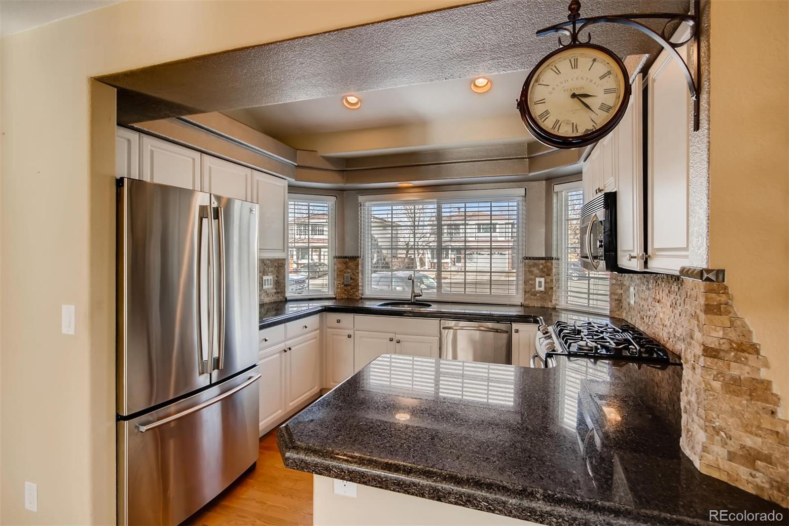 1518 Spring Water Way Highlands Ranch, CO 80129 - Photo 12 of 26 a kitchen with stainless steel appliances granite countertop a refrigerator a stove and a microwave with wooden floor