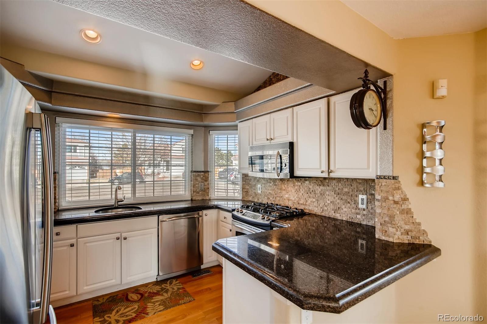 1518 Spring Water Way Highlands Ranch, CO 80129 - Photo 9 of 26 a kitchen with granite countertop a sink a stove and cabinets