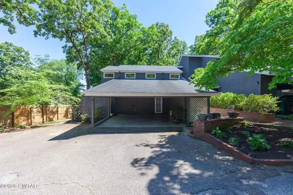 a view of a house with a yard plants and large tree