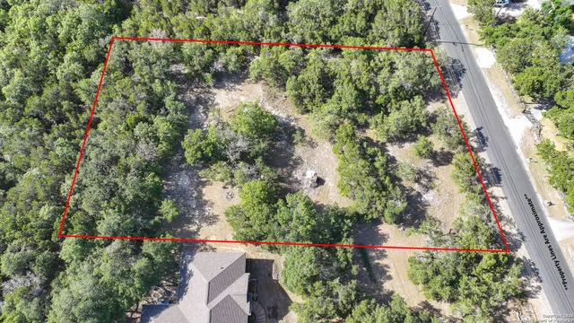 an aerial view of residential house with outdoor space and trees all around