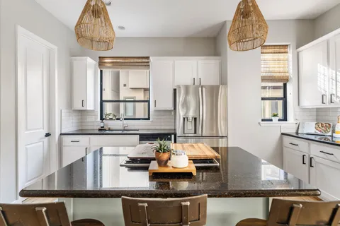 a kitchen with stainless steel appliances granite countertop a sink refrigerator and window