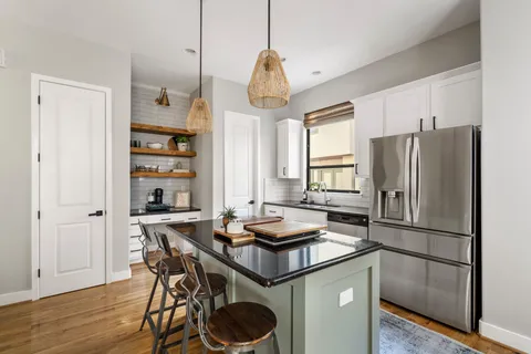 a kitchen with stainless steel appliances granite countertop a table chairs a refrigerator and a window