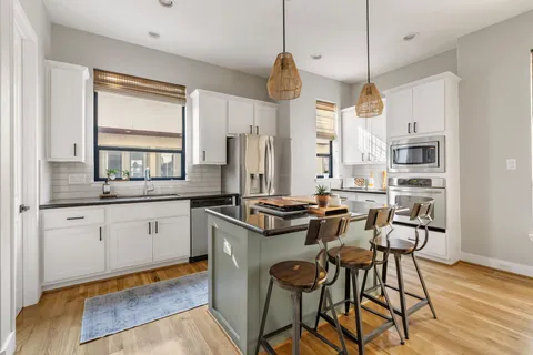 a kitchen with stainless steel appliances granite countertop a stove a sink dishwasher and a refrigerator with wooden floor