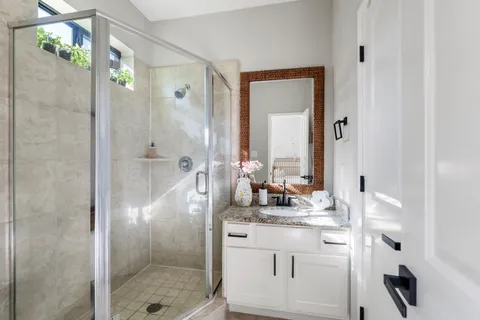 a bathroom with a granite countertop shower sink and mirror