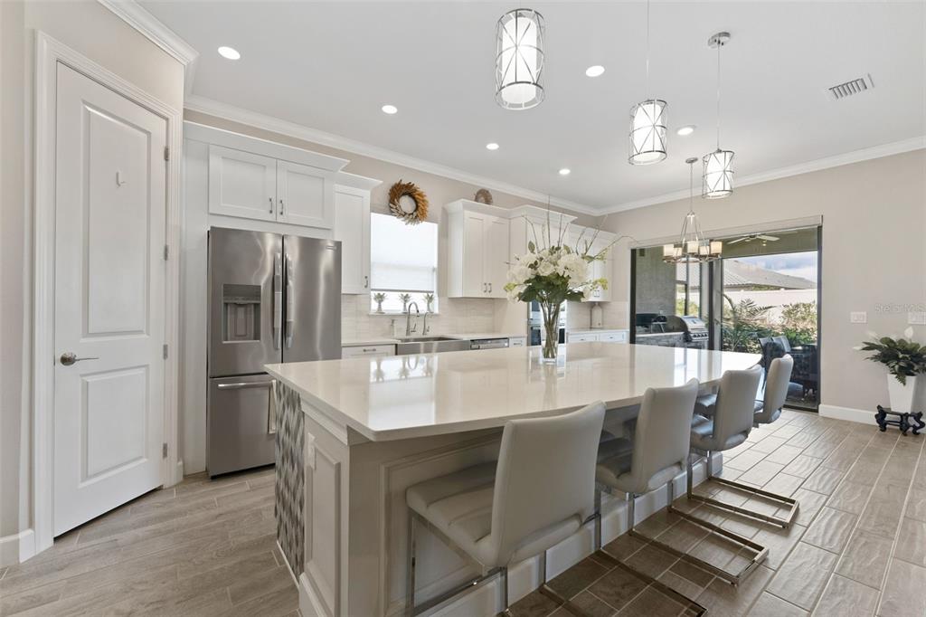 4951 Freccia Loop Wesley Chapel, FL 33543 - Photo 14 of 43 a large white kitchen with a large island oven a sink stainless steel appliances and living room view