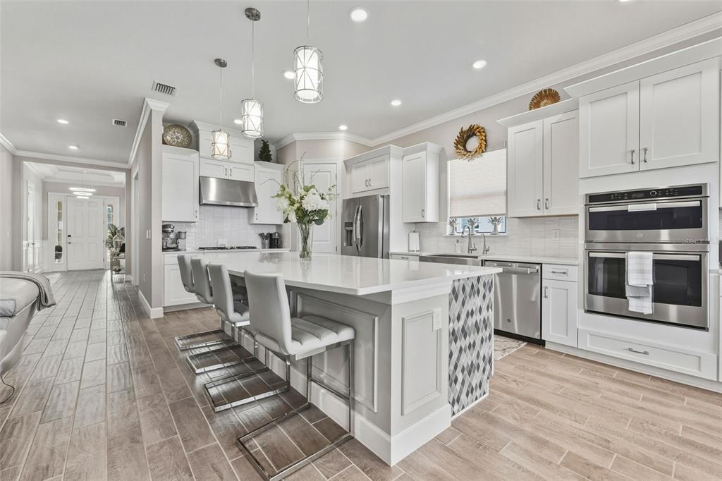 4951 Freccia Loop Wesley Chapel, FL 33543 - Photo 19 of 43 a kitchen with stainless steel appliances kitchen island granite countertop a stove top oven a sink a counter space and cabinets