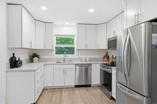 a kitchen with white cabinets sink and stainless steel appliances
