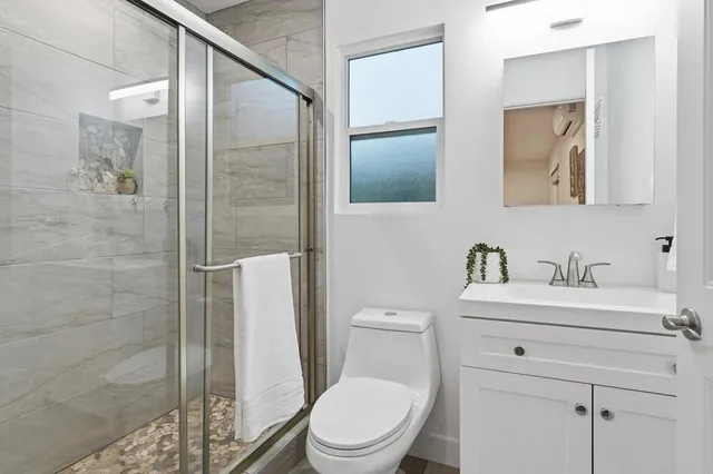 a bathroom with a toilet a sink a glass door a shower and a mirror