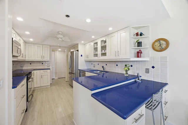 a room with stainless steel appliances kitchen island granite countertop a sink and cabinets