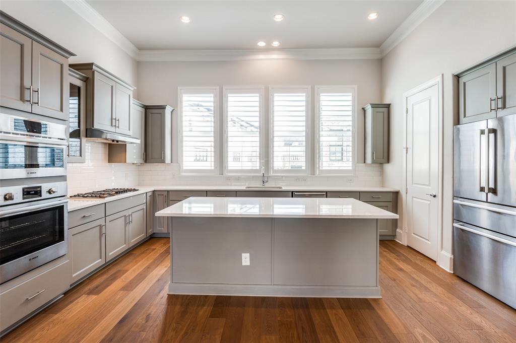 5421 Patterson Street Irving, TX 75039 - Photo 20 of 32 Spacious kitchen featuring an island, light gray cabinetry, stainless steel appliances, white countertops, and wood-finish flooring