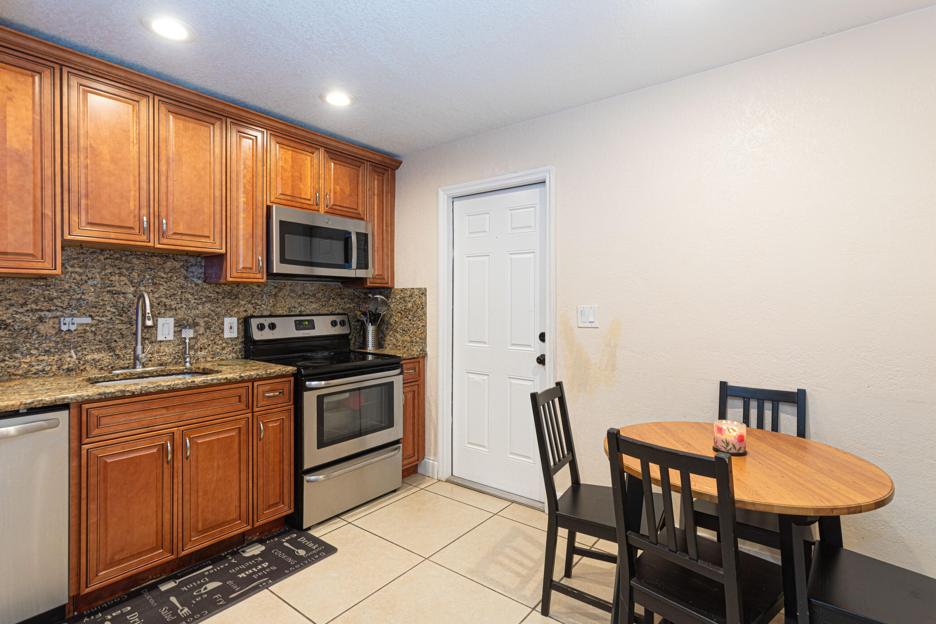 740 Aspen Road West Palm Beach, FL 33409 - Photo 13 of 34 a kitchen with stainless steel appliances granite countertop a stove a sink a microwave a dining table and chairs