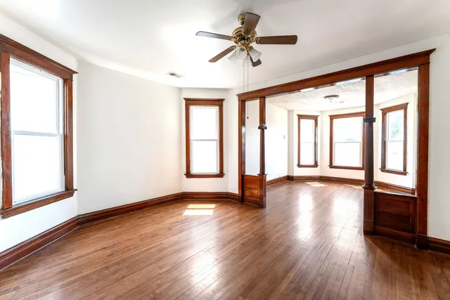 a view of an empty room with wooden floor and a window