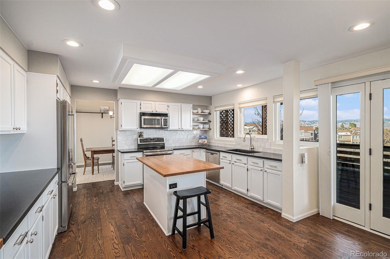9537 Chesapeake Street Highlands Ranch, CO 80126 - Photo 5 of 34 a kitchen with stainless steel appliances granite countertop a refrigerator a sink dishwasher a stove and white countertops with wooden floor