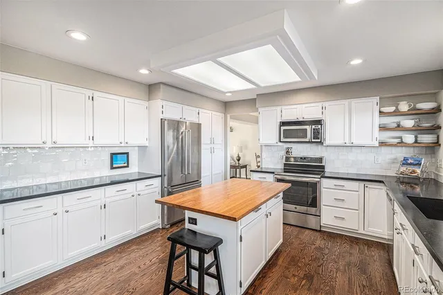 a kitchen with granite countertop a sink stove and refrigerator