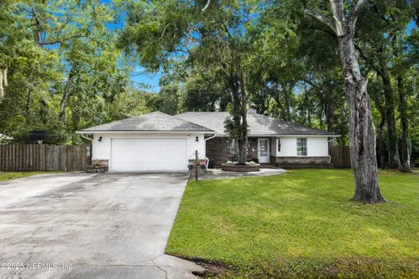 a front view of a house with a garden and trees