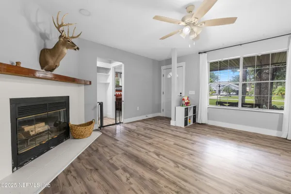 a view of an empty room with wooden floor fireplace and a window