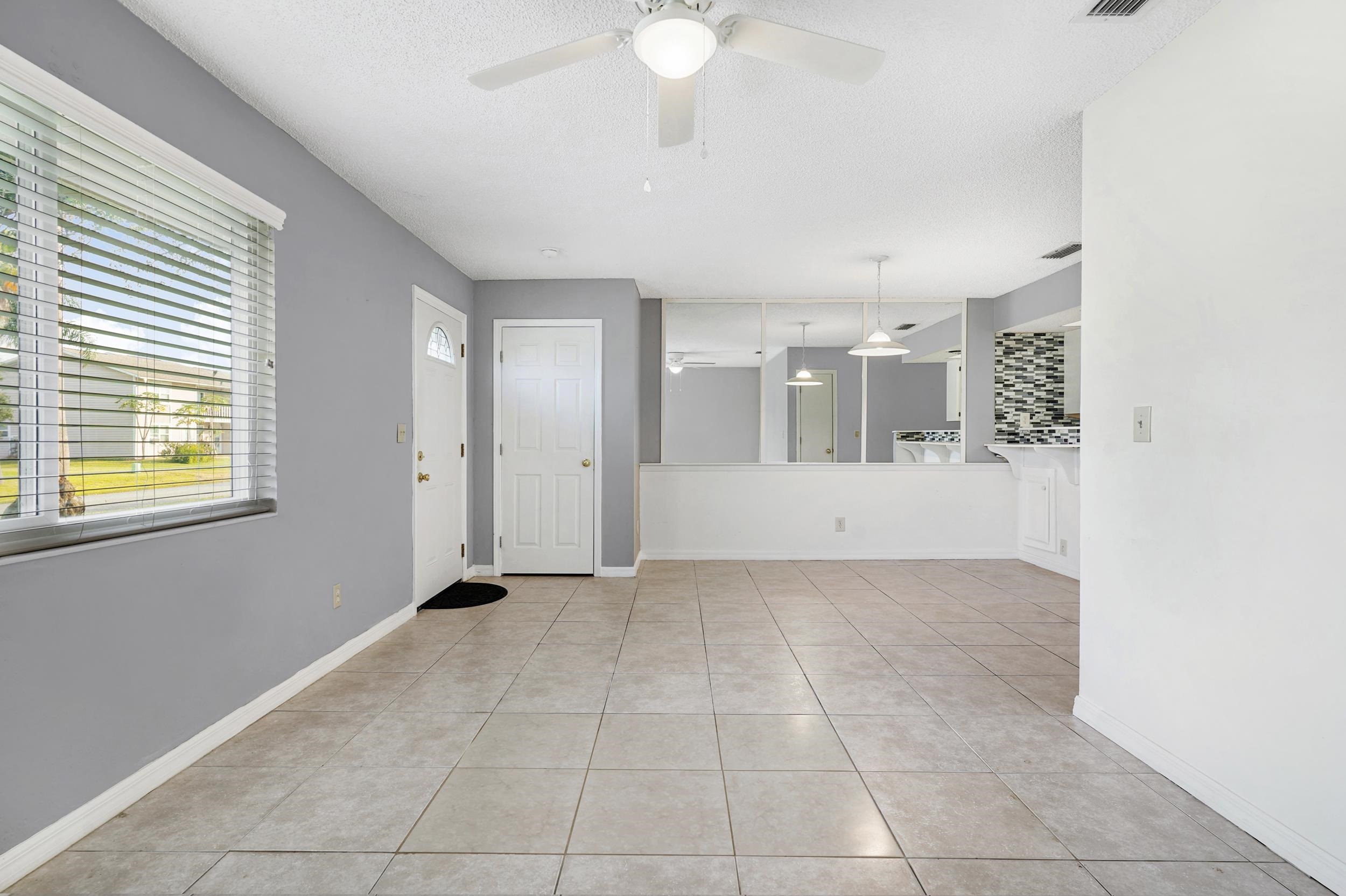 127 Rio Del Mar Street, Unit C St. Augustine, FL 32080 - Photo 11 of 29 Unfurnished living room with light tile patterned flooring, a ceiling fan, and a textured ceiling