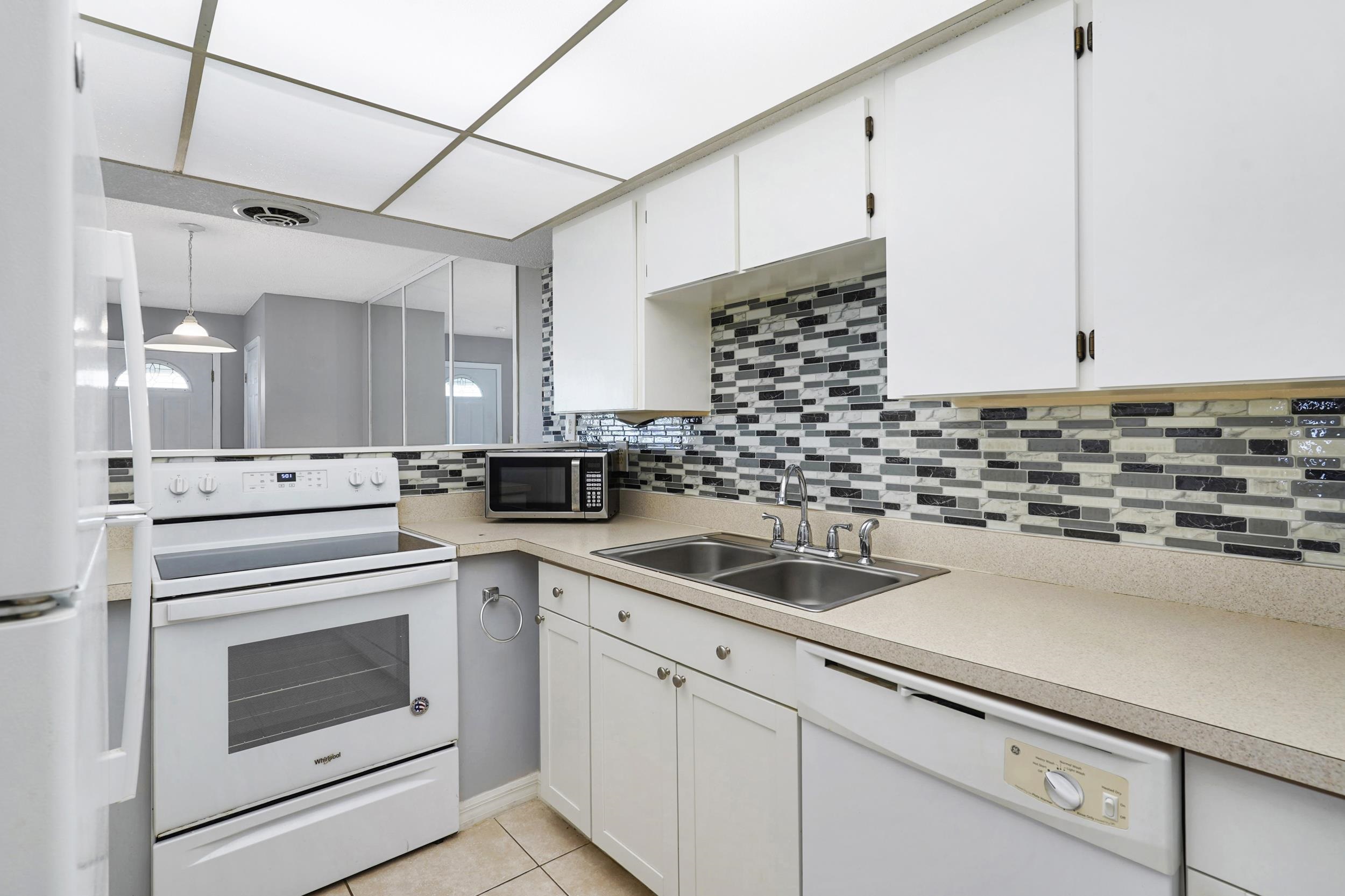 127 Rio Del Mar Street, Unit C St. Augustine, FL 32080 - Photo 8 of 29 Kitchen with white appliances, light countertops, tasteful backsplash, pendant lighting, and white cabinetry