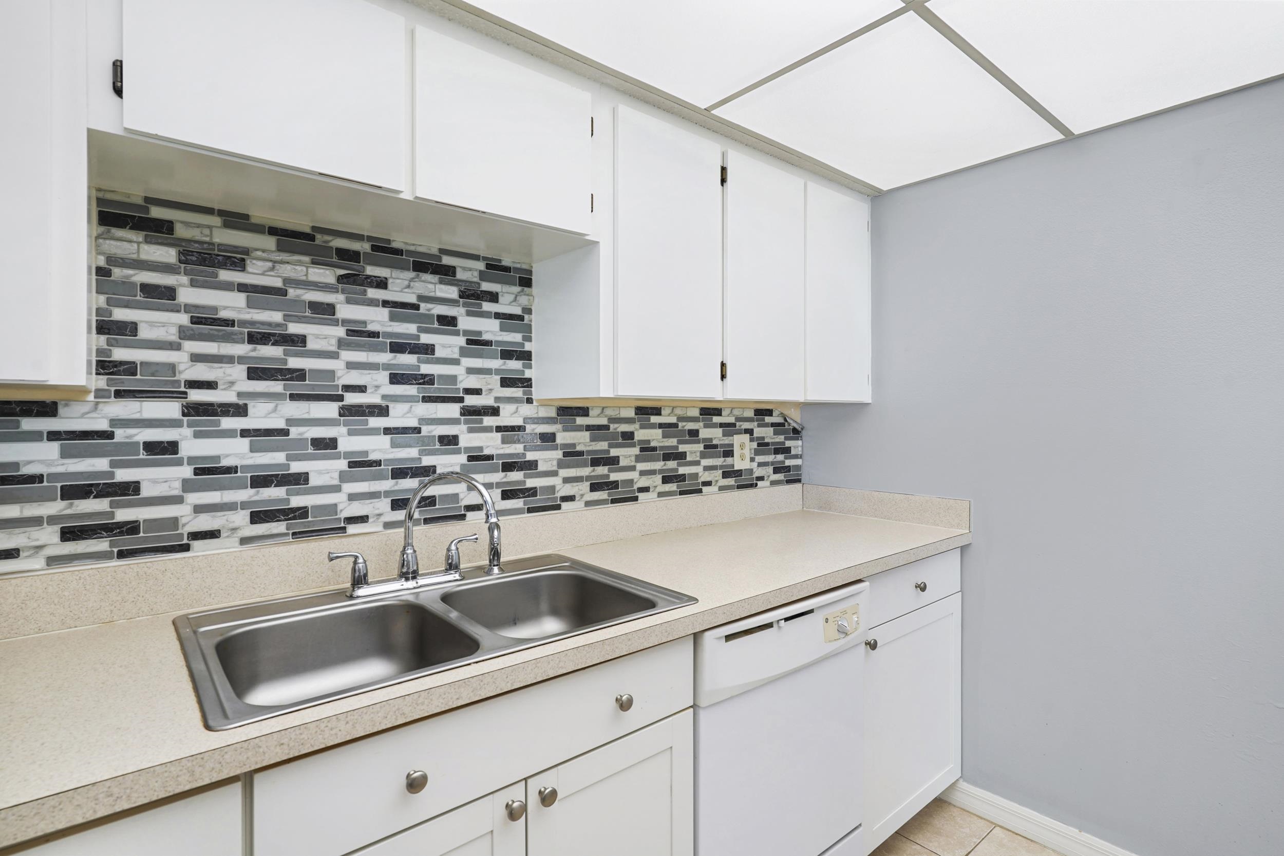 127 Rio Del Mar Street, Unit C St. Augustine, FL 32080 - Photo 9 of 29 Kitchen featuring light countertops, dishwasher, white cabinetry, backsplash, and light tile patterned floors
