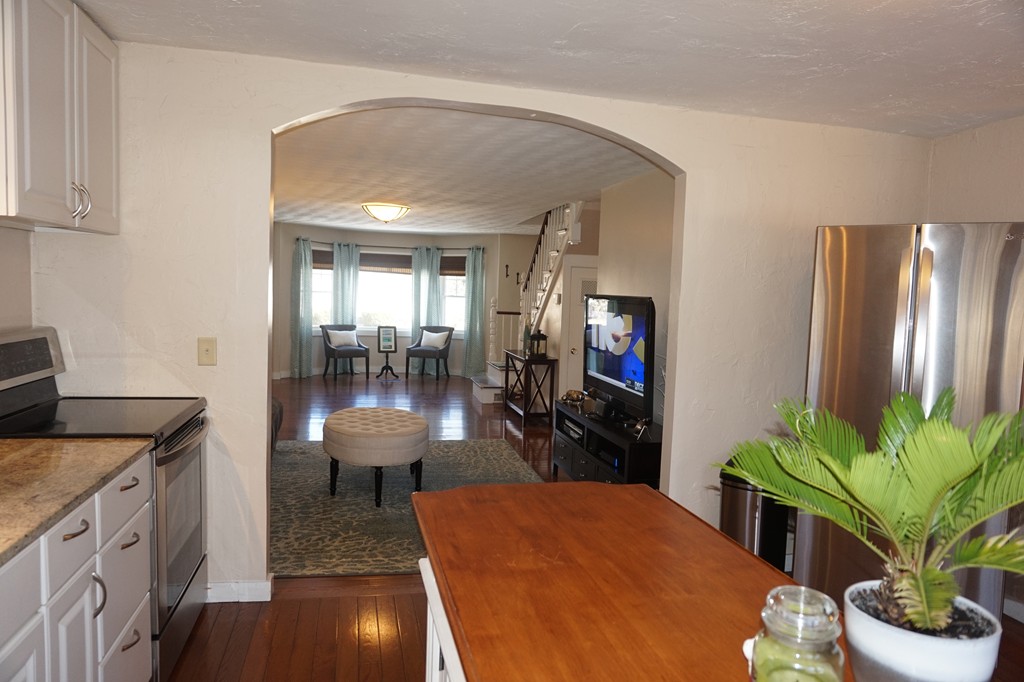 329 Mill Street Lancaster, MA 01523 - Photo 8 of 30 a kitchen with stainless steel appliances kitchen island granite countertop a refrigerator a stove a sink a dining table and chairs with wooden floor